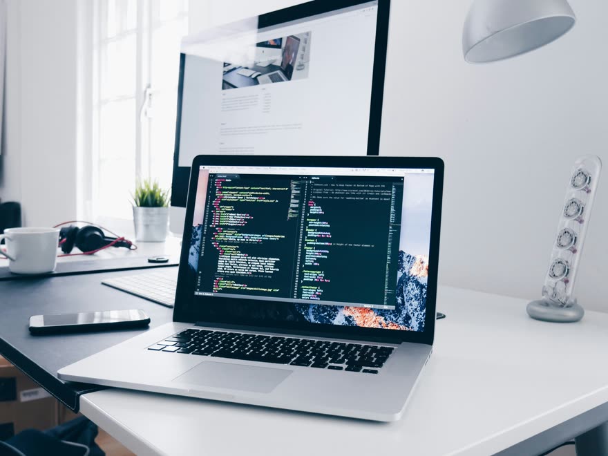 Linhas de código exibidas em um monitor sobre uma mesa de trabalho.